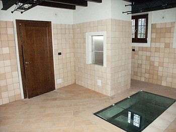 Vista interno rustico con cristallo a pavimento per l'osservazione delle antiche mura.